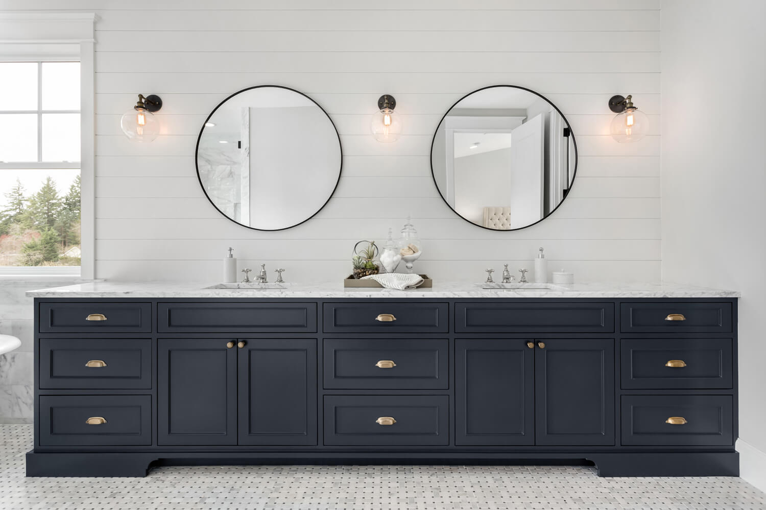 A Bathroom Vanity with Two Sink Bowls, Two Mirrors, a Marble Countertop, and Black Drawers and Cabinets