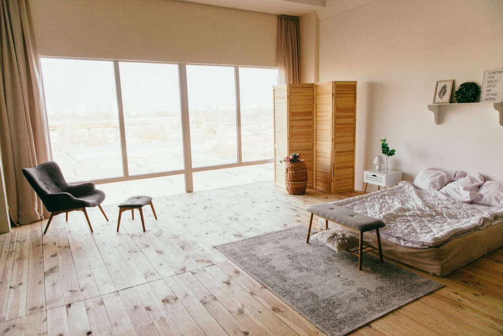 A Bedroom with an Interior Design Featuring a Wooden Divider, Floorboards, and Luggage Rack, a Mattress for a Bed, and Other Things 