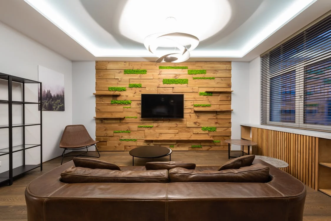  a brown leather sofa facing a paneled wall with a TV